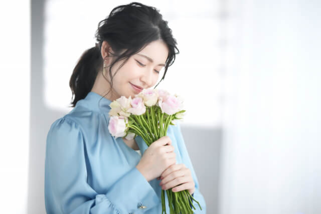 花の香りを嗅ぐ女性