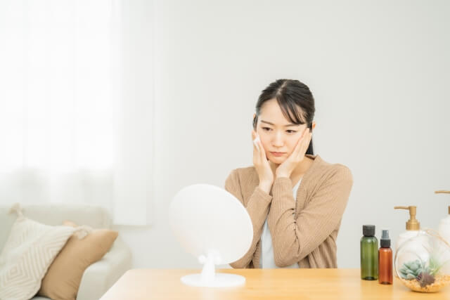 鏡の前で肌に悩む女性